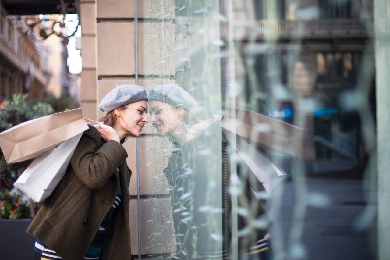 Mulher segurando sacola de compras olhando a vitrine