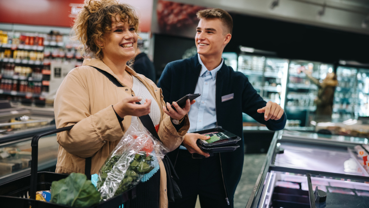 jovem funcionário de um supermercado e uma cliente satisfeita, representando uma bom modo como captar clientes.