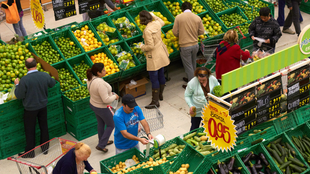 Uma comunicação visual para supermercados em uma feirinha, com pessoas fazendo compras.