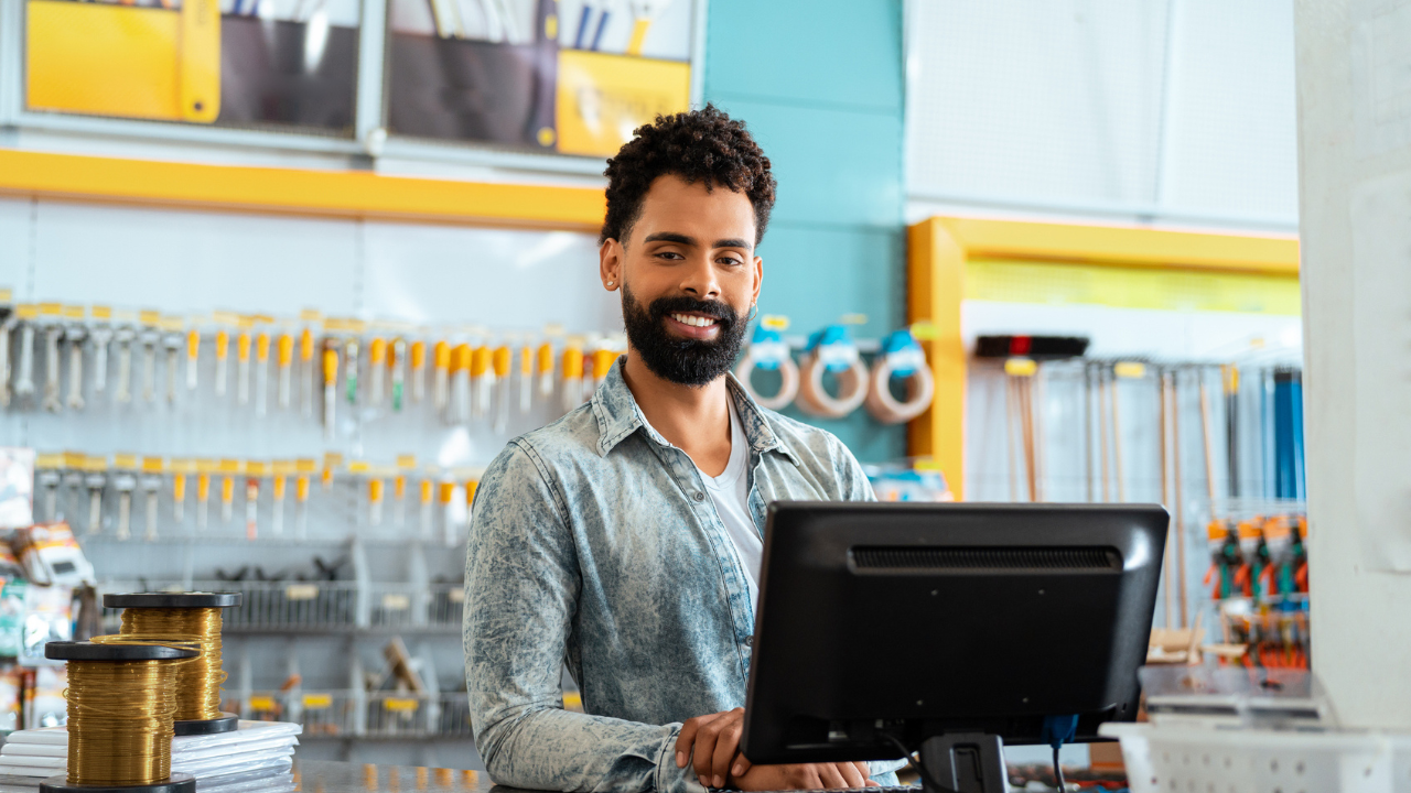 Vendedor em loja de materiais de construção utilizando computador, representando estratégia omnichannel no varejo