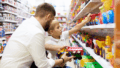 Pai e filho observam juntos prateleiras cheias de brinquedos coloridos em uma loja, simbolizando o movimento do dia das crianças no varejo e o impacto emocional das compras nesta data especial.