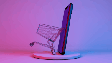 um carrinho de supermercado ao lado de um aparelho celular, os dois estão virados de lado